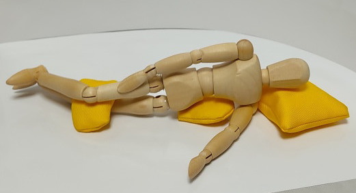 多目的枕の使用例。脇腹と膝をサポートする使い方。横臥位時の姿勢が安定し、首と肩にかかる負荷を軽減できます。